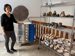 Ceramista Simoni Nishimura posa ao lado do forno de alta temperatura no ateliê Shoyu Crafts