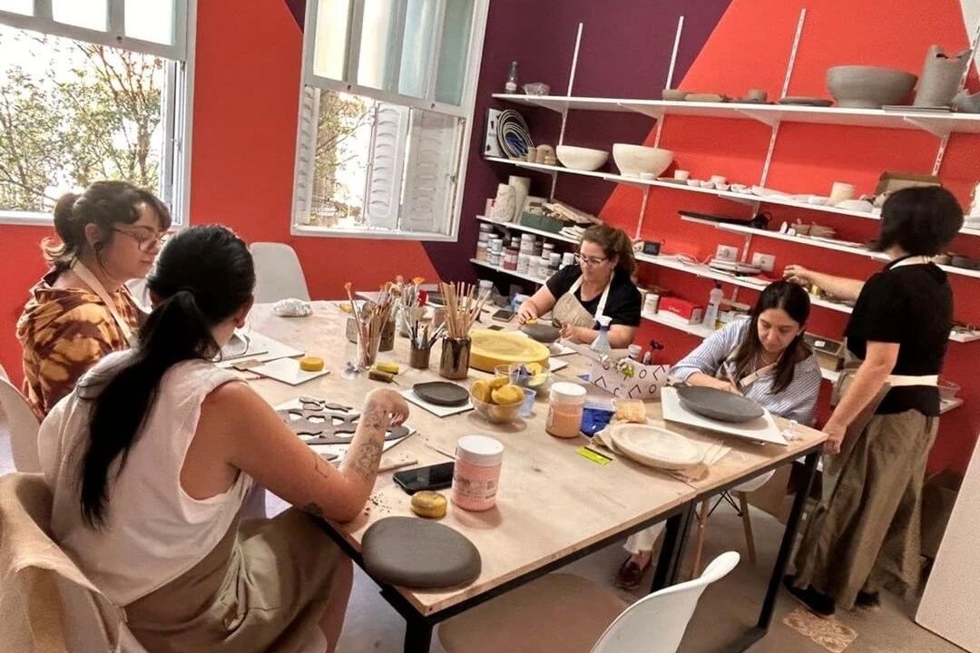 Pai mostra mãos sujas de argila durante modelagem em Oficina Familiar com o filho