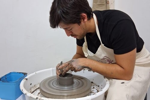 Aluno em aula de modelagem cerâmica no torno elétrico